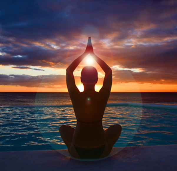 Adult sitting in yoga pose at sunset
